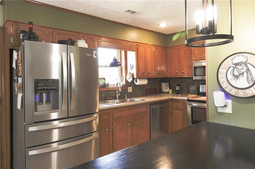 249 Cooper Road Southeast Calhoun, GA 30701 - Photo 16 of 62 a kitchen with stainless steel appliances granite countertop a refrigerator a stove and a sink with large window