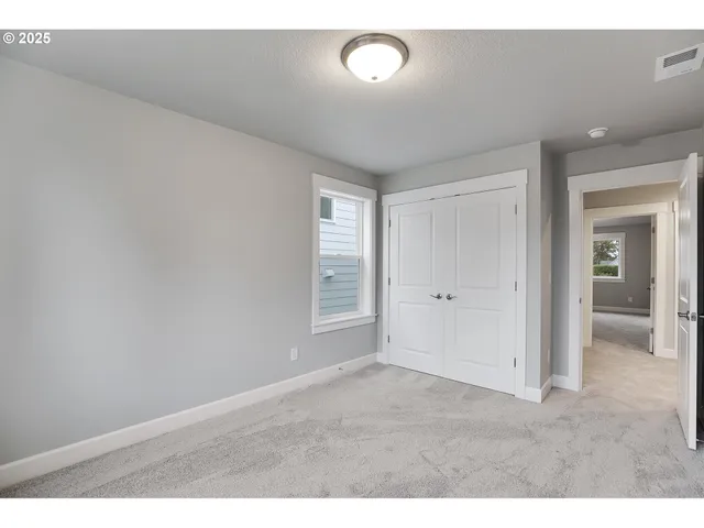 a view of an empty room with closet and a window