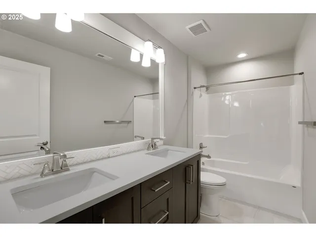 a bathroom with a sink double vanity granite tub shower and a mirror