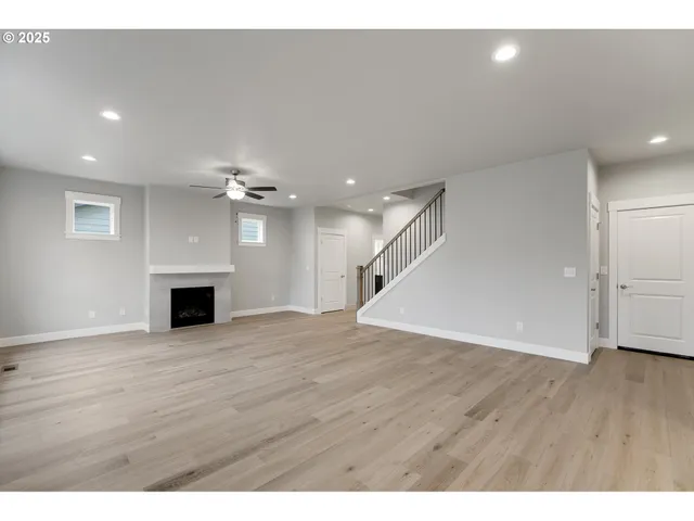 a view of a livingroom with a ceiling fan fireplace and wooden floor