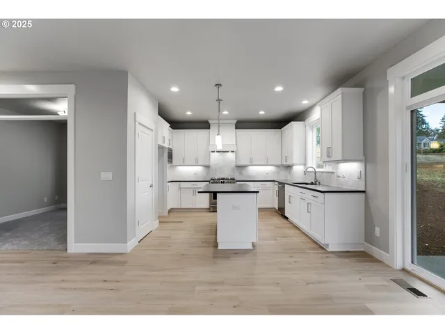 a kitchen with stainless steel appliances kitchen island granite countertop a refrigerator a sink and a stove