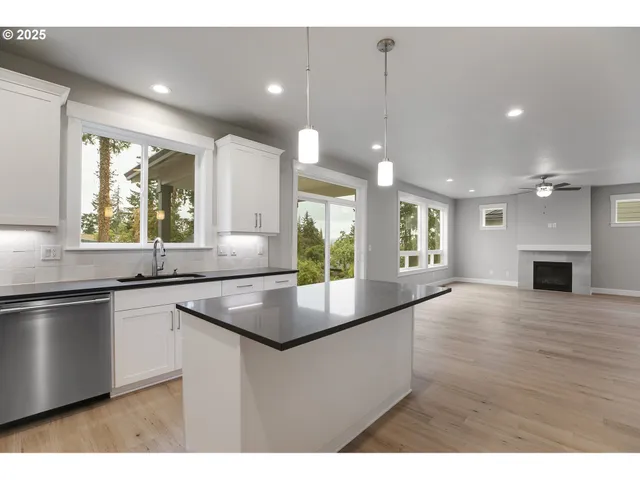 a kitchen with stainless steel appliances granite countertop a sink a stove and a wooden floors