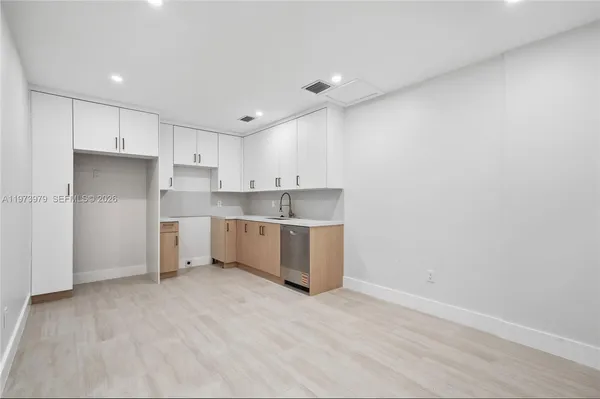 a view of a kitchen with white cabinets and wooden floor