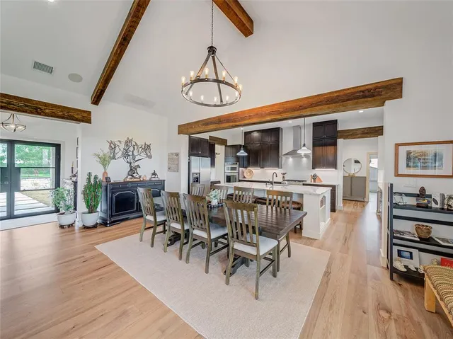a dining room with wooden floor a chandelier a glass table and chairs