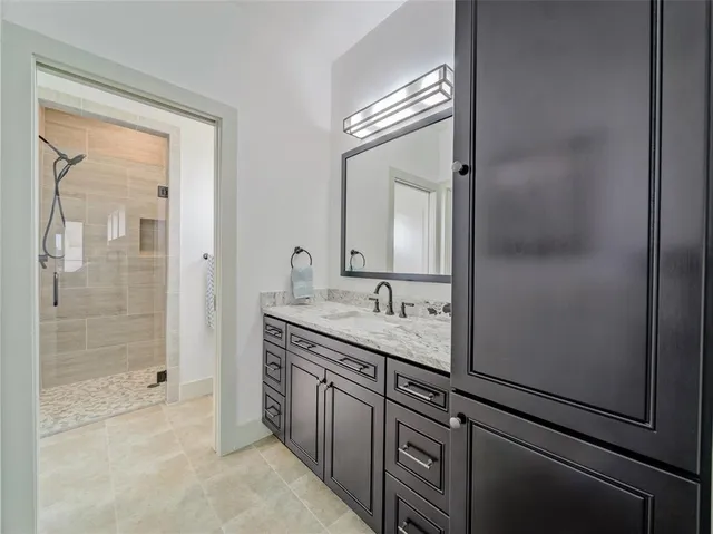 a bathroom with a granite countertop sink a mirror and a shower