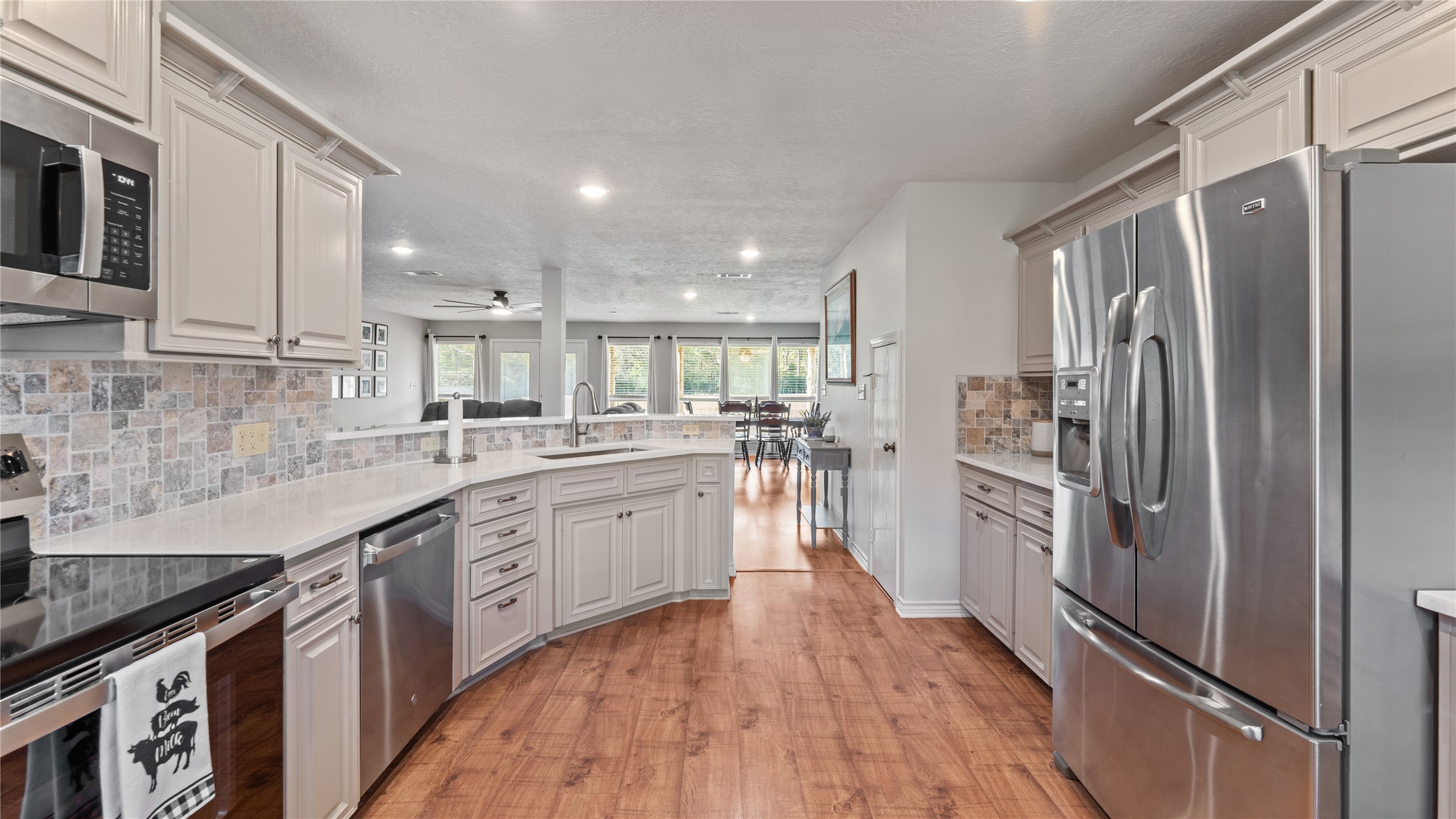 245 Alabama Point Livingston, TX 77351 - Photo 11 of 50 a large kitchen with stainless steel appliances granite countertop a refrigerator a sink dishwasher a stove and white cabinets with wooden floor