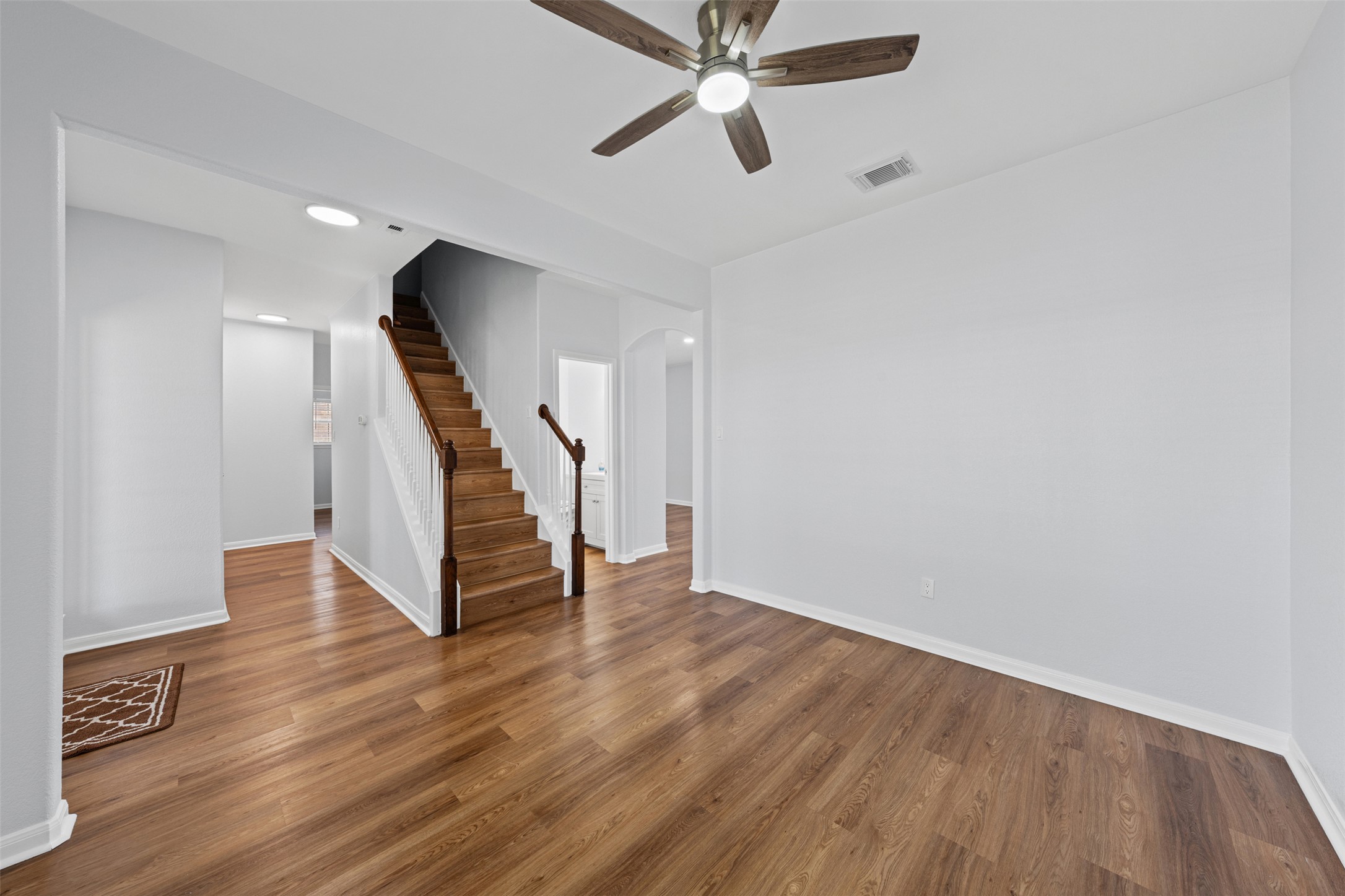 243 Engineers Pass Jarrell, TX 76537 - Photo 4 of 40 Room featuring wood-finish flooring, a ceiling fan with light fixture, white painted walls, white baseboards, and an interior staircase with wood treads and white risers
