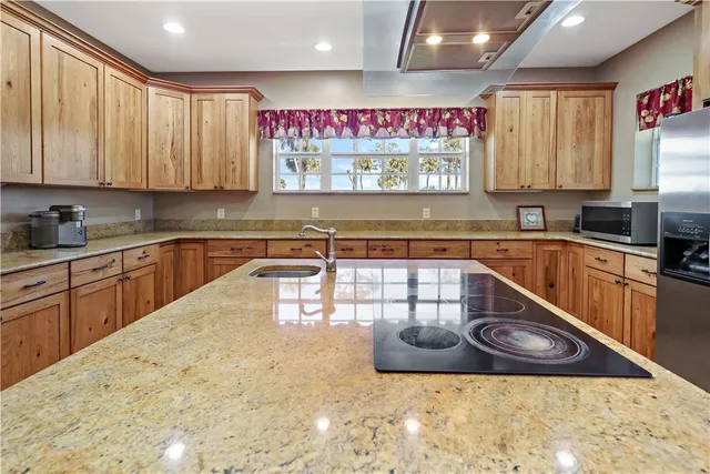 a kitchen with kitchen island granite countertop a sink a counter top space and cabinets