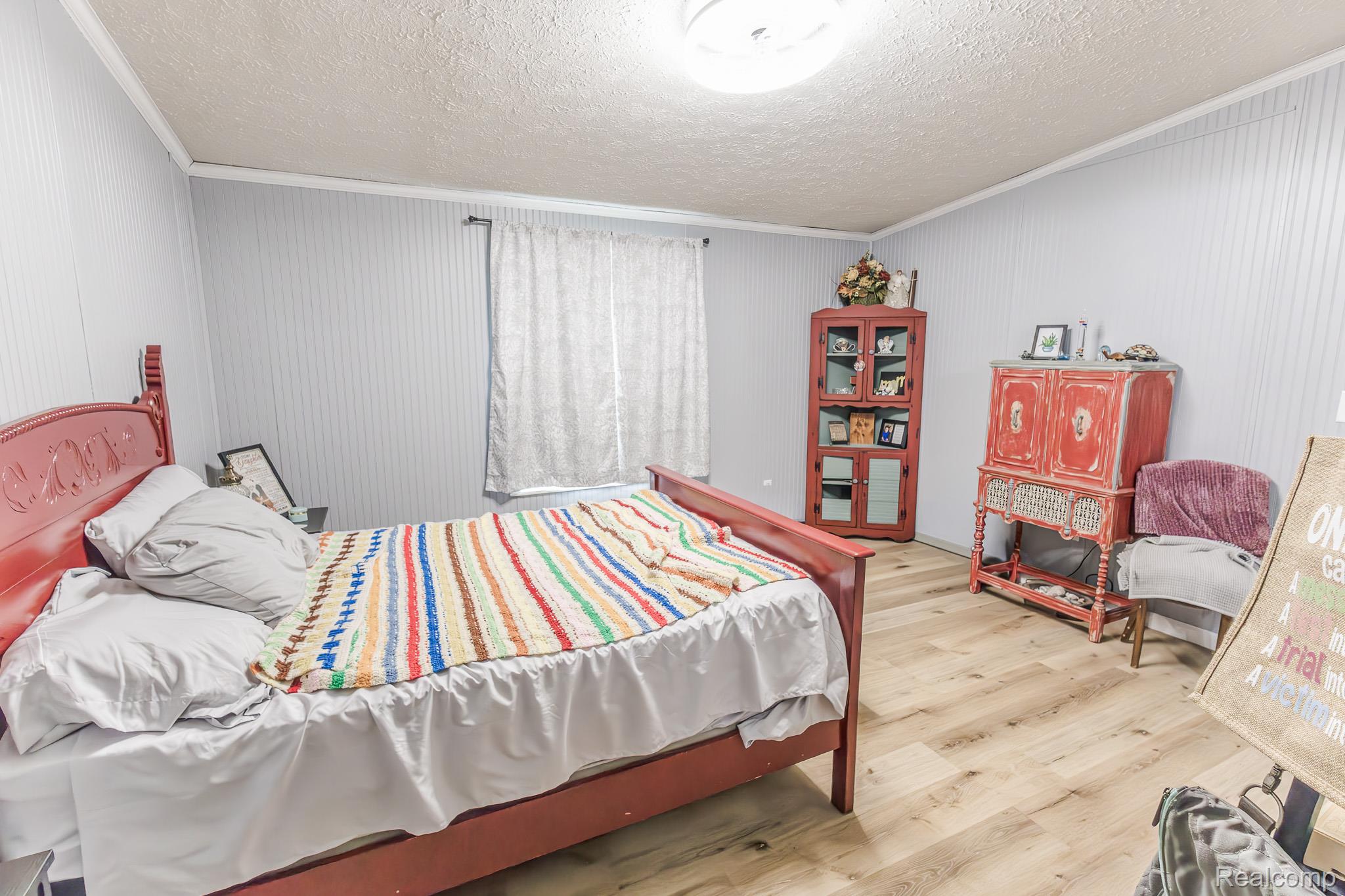2649 Brown Road Millington, MI 48746 - Photo 13 of 18 Spacious bedroom featuring warm wood-finish flooring, a red metal bed frame, and ample natural light from multiple windows