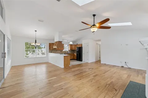 a view of a kitchen with a stove a kitchen island wooden floor and ceiling fan