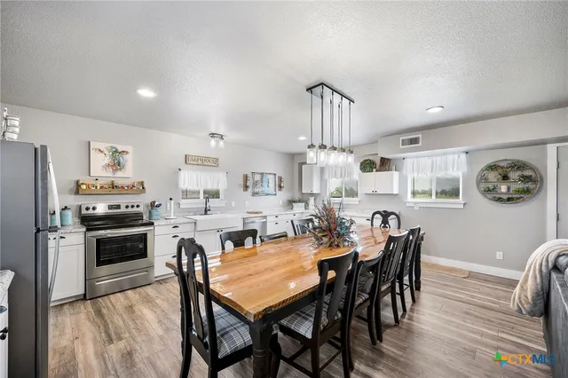 a view of kitchen with stainless steel appliances granite countertop a stove a sink dishwasher and a refrigerator with wooden floor