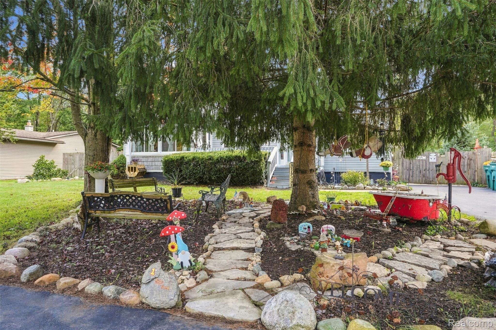 36739 Wick Road Romulus, MI 48174 - Photo 37 of 56 Mature evergreen trees, stone-edged garden beds with mulch, flagstone pathway, and a red decorative pump feature