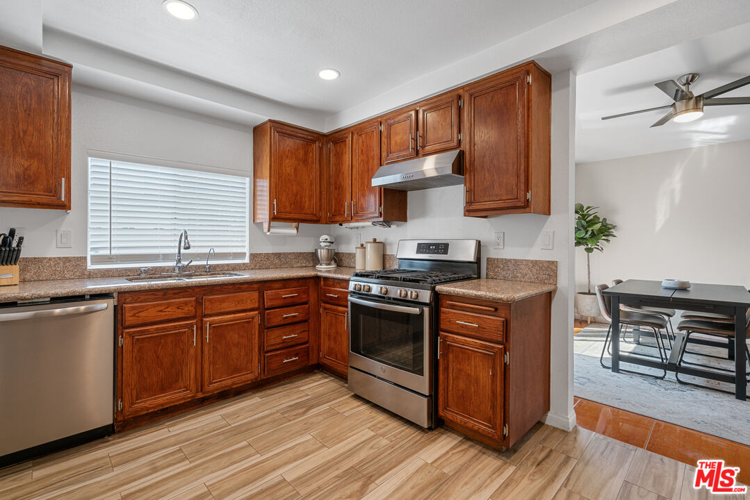 12309 Clover Road Pacoima, CA 91331 - Photo 6 of 15 a kitchen with stainless steel appliances granite countertop wooden cabinets a sink a stove a dining table and chairs