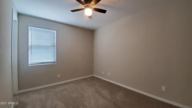 an empty room with a window and a fan