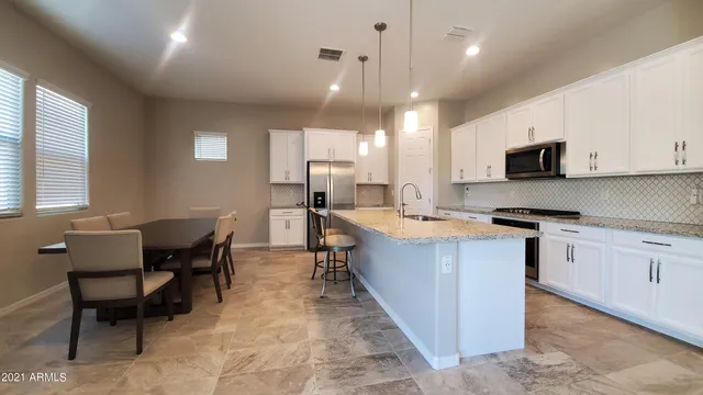 a large kitchen with stainless steel appliances kitchen island granite countertop a sink a stove a dining table and chairs