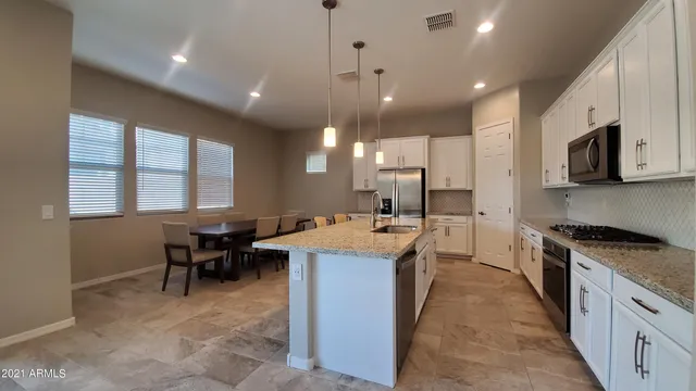a large kitchen with lots of furniture a sink a counter space and stainless steel appliances