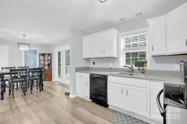 a kitchen with stainless steel appliances granite countertop a stove a sink a dining table and chairs with wooden floor