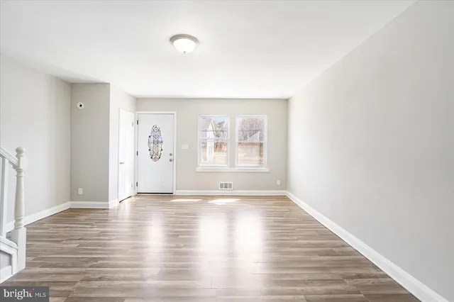 a view of an empty room with window and wooden floor