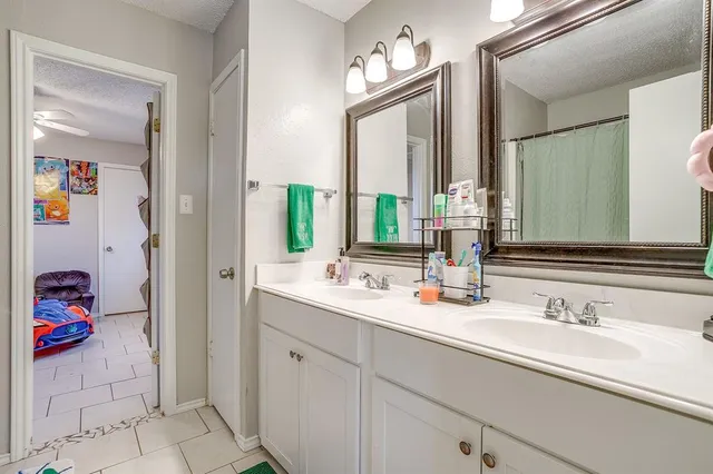 a en suite bathroom with a double vanity sink a toilet and a mirror