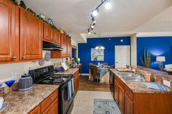 a kitchen with stainless steel appliances granite countertop a stove a sink dishwasher and a refrigerator with wooden cabinets