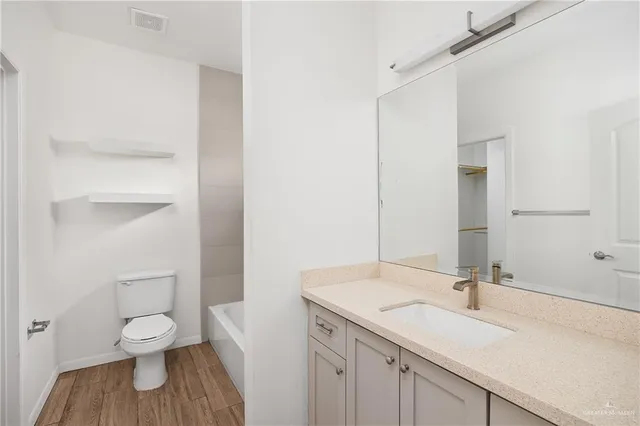 a bathroom with a granite countertop sink a toilet and a large mirror