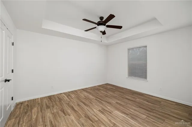 a view of empty room with wooden floor and ceiling fan