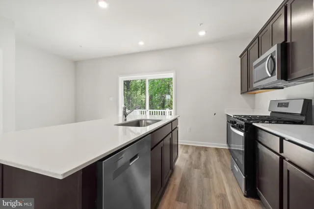 a view of an empty room with wooden floor and a kitchen
