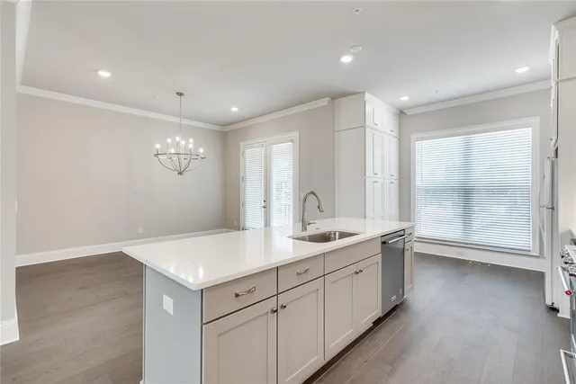a view of a kitchen with a sink and dishwasher with wooden floor