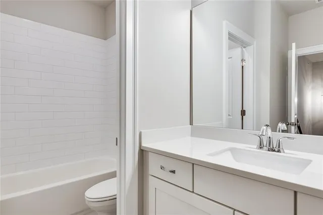 a bathroom with a bathtub shower sink vanity and toilet
