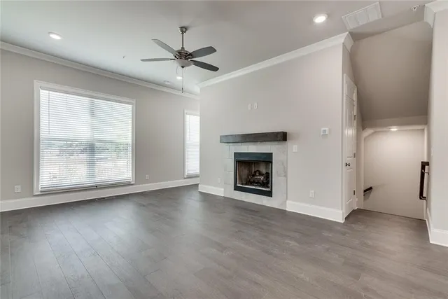 an empty room with wooden floor a ceiling fan and windows