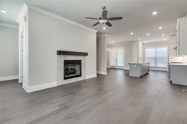 a view of an empty room and kitchen with fireplace wooden floor