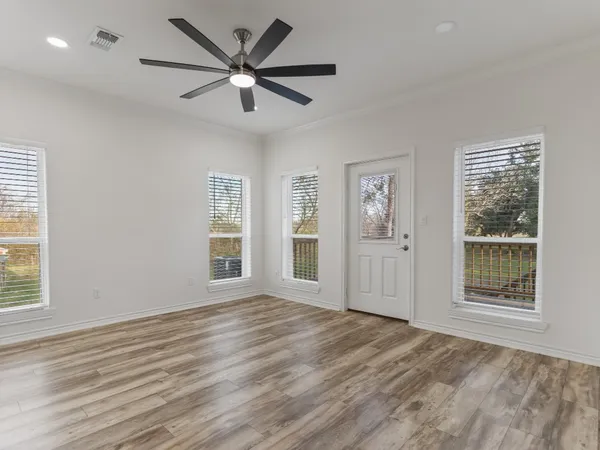 a view of an empty room with a window and wooden floor