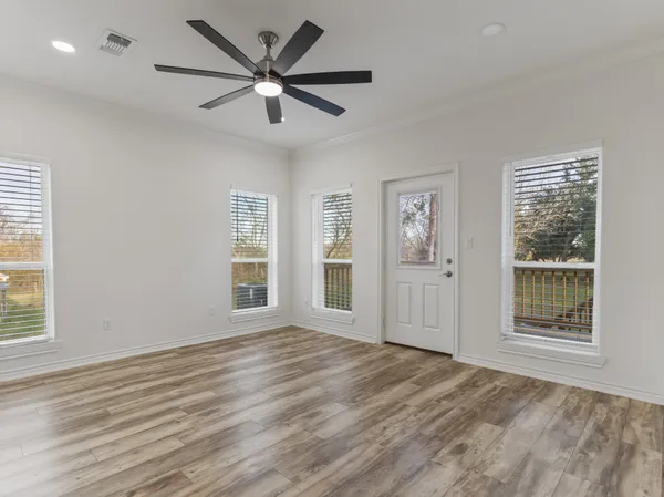 a view of an empty room with a window and wooden floor