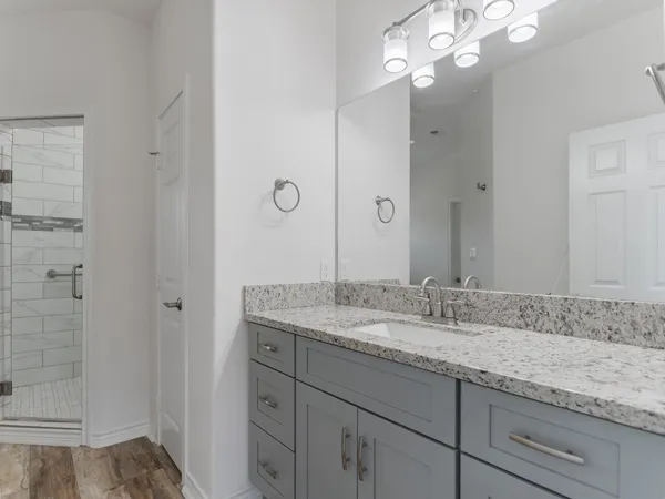 a bathroom with a granite countertop sink a mirror and shower