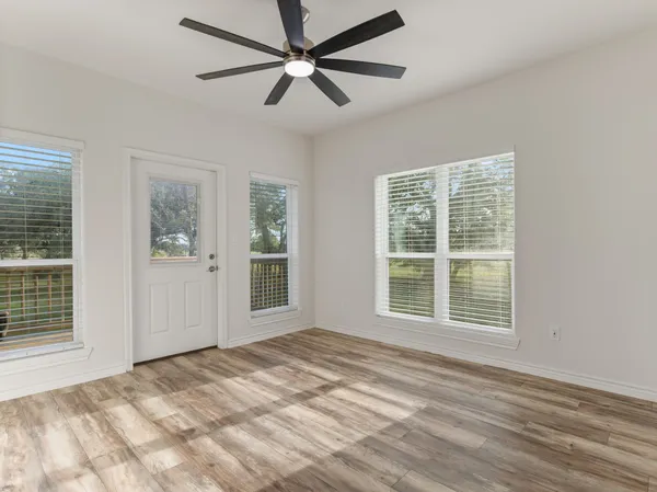a view of an empty room with a window and wooden floor