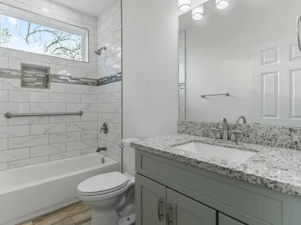 a bathroom with a granite countertop toilet a sink and bathtub