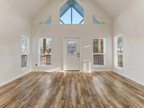 a view of an empty room with a window and wooden floor