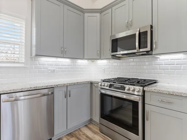 a kitchen with granite countertop white cabinets stainless steel appliances and sink
