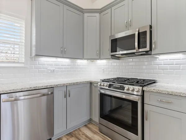 a kitchen with granite countertop white cabinets stainless steel appliances and sink