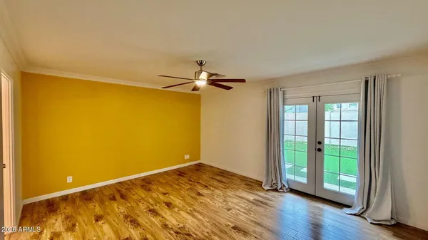 a view of empty room with wooden floor and fan