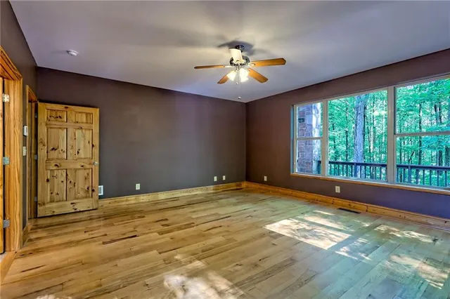 a view of empty room with window and wooden floor