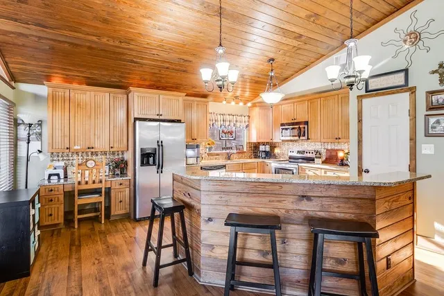 a view of a kitchen with kitchen island granite countertop wooden floor and stainless steel appliances