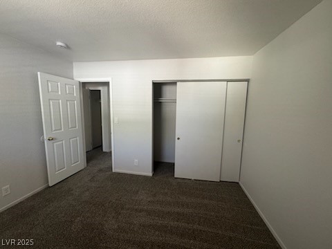 4360 Twin View Circle, Unit 4 Las Vegas, NV 89121 - Photo 10 of 17 Unfurnished bedroom with dark carpet, a textured ceiling, and a closet