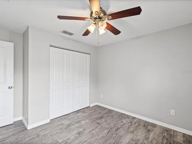 wooden floor in an empty room with a chandelier fan