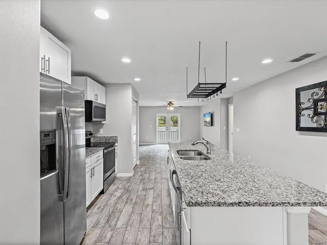 a kitchen with stainless steel appliances kitchen island granite countertop a sink refrigerator and cabinets