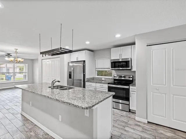 a kitchen with stainless steel appliances granite countertop a sink and a refrigerator