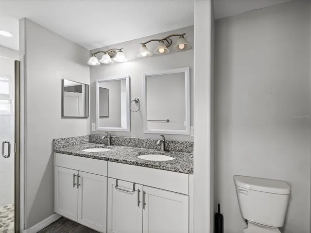 a bathroom with a granite countertop sink mirror and toilet