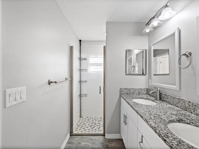 a bathroom with a granite countertop sink mirror and shower