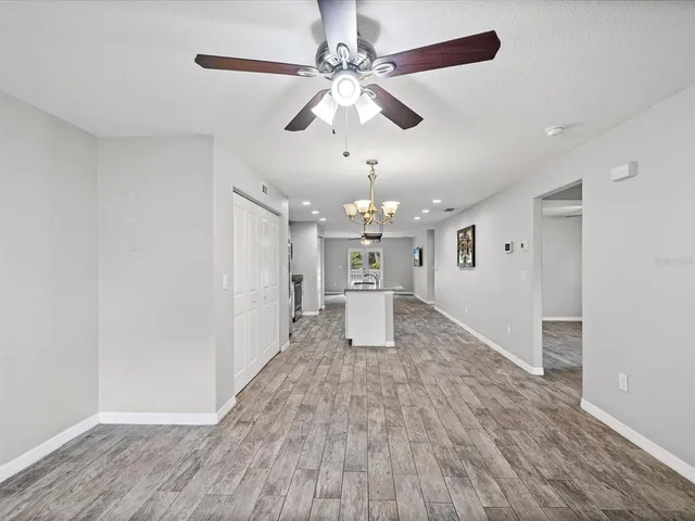 wooden floor in an empty room with a chandelier fan