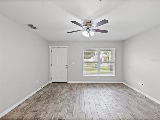 a view of empty room with wooden floor and fan